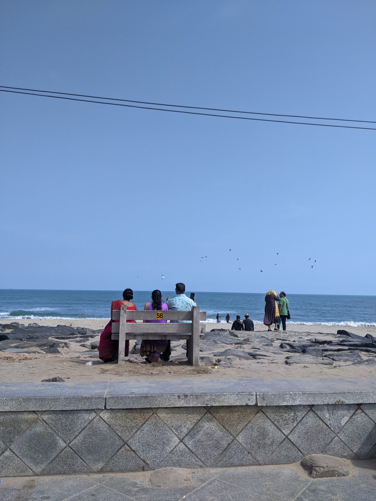 People sitting on a bench facing the sea 